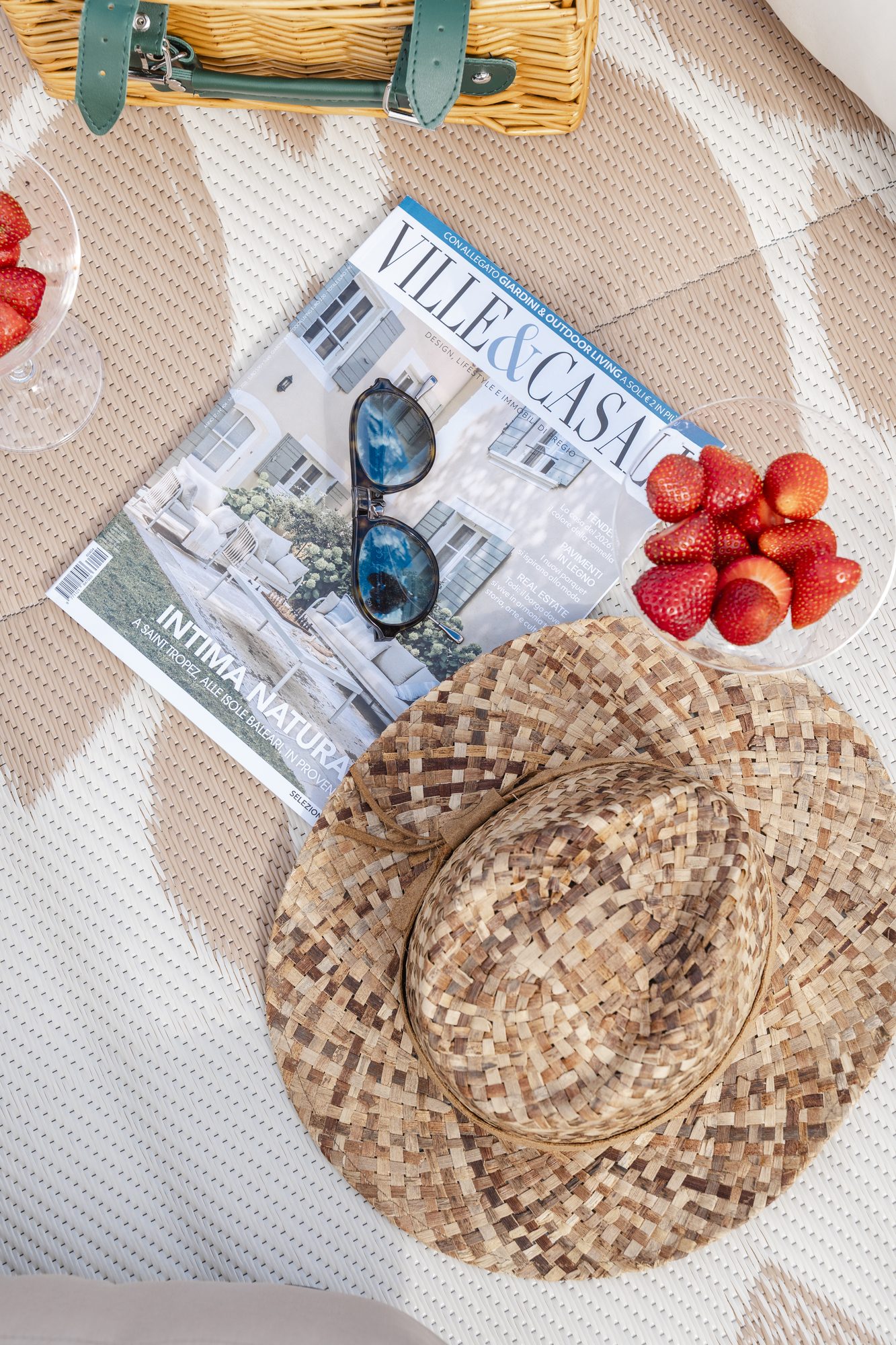 Rivista, cappello di paglia e fragole accanto alla piscina